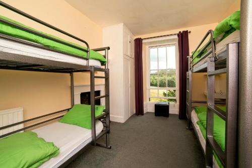 a room with three bunk beds and a window at YHA Coniston Holly How in Coniston