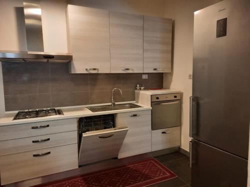 uma cozinha com armários de madeira e um frigorífico de aço inoxidável em Appartamento su palazzina storica in centro a Sant'Antioco em SantʼAntìoco