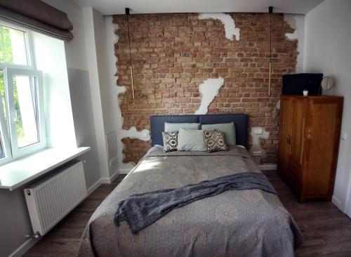 a bedroom with a brick wall and a bed at Comfortable design apartment with parking in Rīga