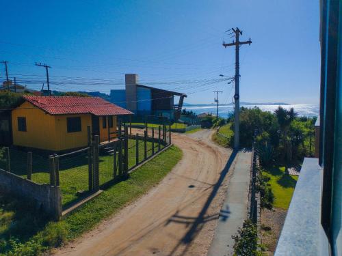 a dirt road with a yellow house on the side at Residence Farol - Loft 206 in Laguna
