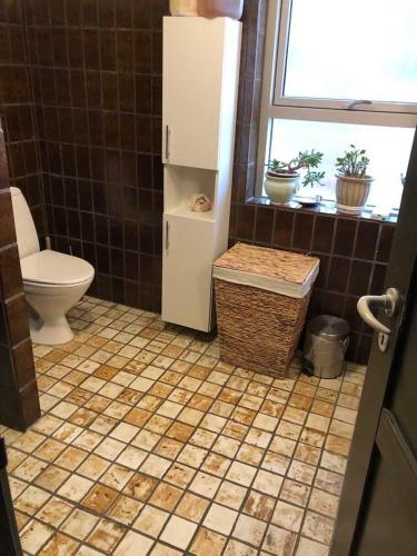 a bathroom with a toilet and a tiled floor at Maren's apartment on Randbøl Heath in Randbøl