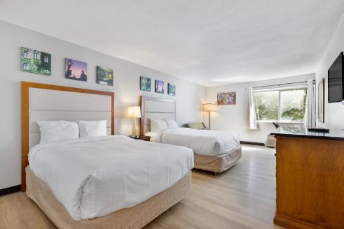 a hotel room with two beds and a flat screen tv at Days Inn by Wyndham Erie in Erie