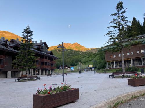 a courtyard with benches and buildings with mountains in the background at Casa Dalja in Abetone