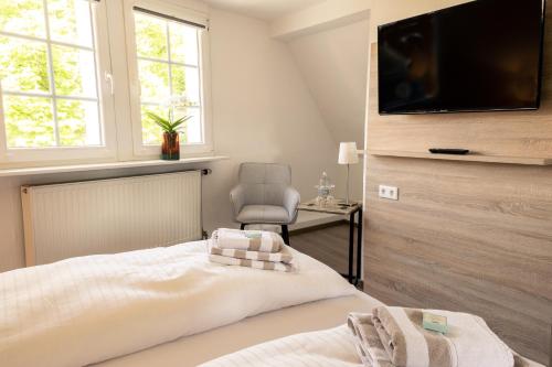 a bedroom with a bed with a television on the wall at HeimatHerz Hotel Garni in Herdecke