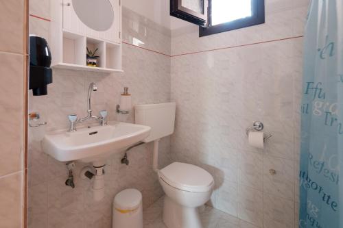La petite salle de bains est pourvue de toilettes et d'un lavabo. dans l'établissement Mouzakitis Apartments 3, à Arillas