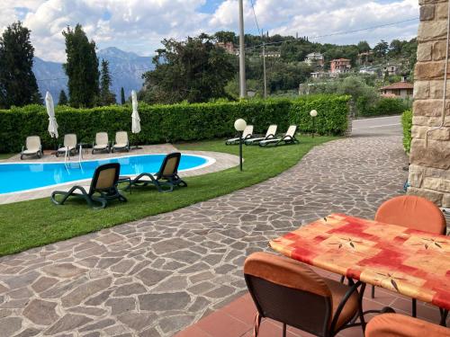 eine Terrasse mit einem Tisch und Stühlen neben einem Pool in der Unterkunft Apartments Panoramica in Malcesine