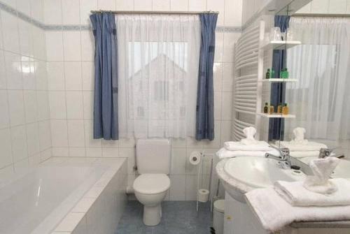 a white bathroom with a tub and a toilet and a sink at Le Bernister parking privé in Malmedy