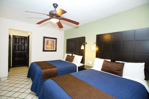 Habitación de hotel con 2 camas y ventilador de techo. en Hotel Posada Terranova en San José del Cabo