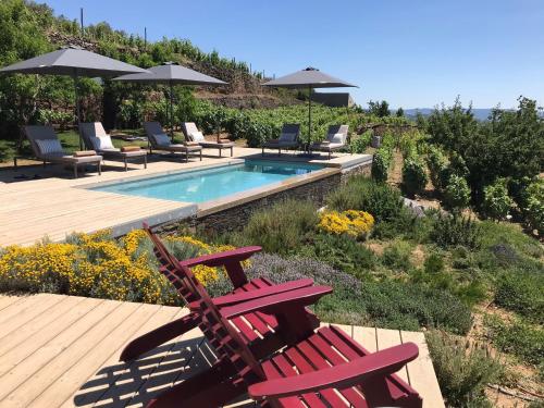 a pair of red chairs sitting next to a swimming pool at Casa de Pena d'Águia - Douro Encantado in Provesende