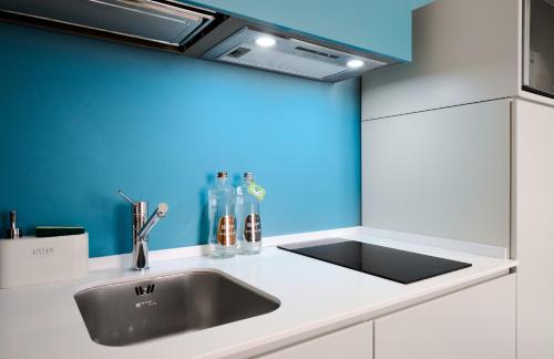 a kitchen with a sink and a blue wall at Donatello 11 Milan apartments in Milan