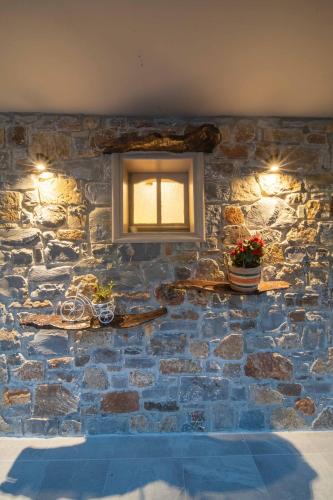 a stone wall with a window and flowers on it at Krassopsychia Apartments in Krásion