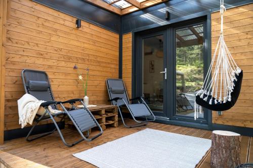 a screened porch with three chairs and a hammock at Uroczy mały domek na leśnej działce - Łosiówka in Łosie