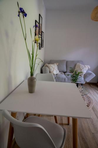 a white dining room table with a vase of flowers on it at Uroczy mały domek na leśnej działce - Łosiówka in Łosie