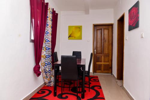 uma sala de jantar com uma mesa e cadeiras num tapete vermelho em Studio lumineux em Douala