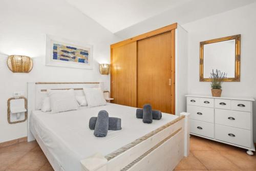 a bedroom with a white bed and a wooden cabinet at Villa Gloria in Cala'n Bosch