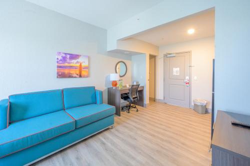 a living room with a blue couch and a desk at Hawthorn Extended Stay by Wyndham Panama City Beach in Panama City Beach