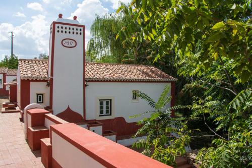 a building with a clock tower next to some trees at Hotel Rural Monte da Provença in Elvas