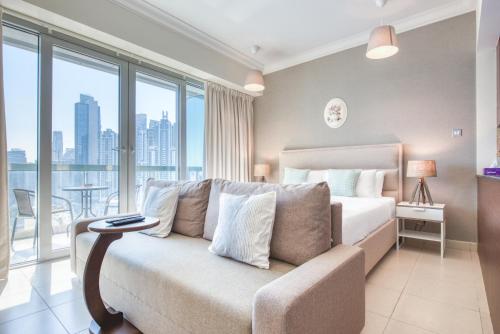 a bedroom with a bed and a couch and windows at Prime Retreats - Downtown Dubai in Dubai