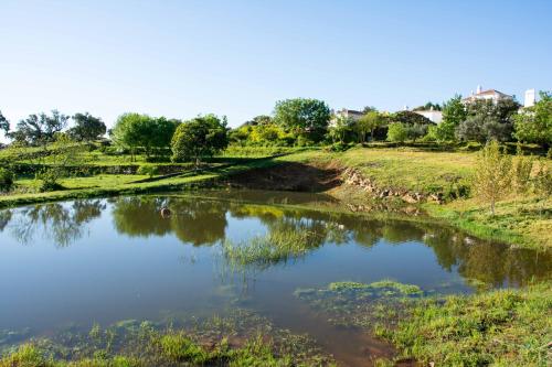 a pond in a field next to a river at Hotel Rural Monte da Provença in Elvas