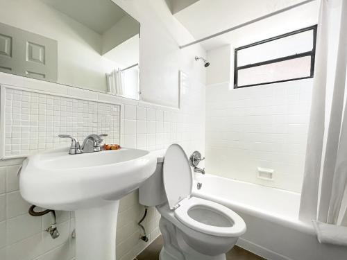 Baño blanco con lavabo y aseo en Silver Spray Motel, en Hollywood