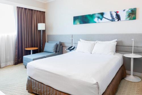 a hotel room with a large bed and a chair at Crowne Plaza Managua by IHG in Managua