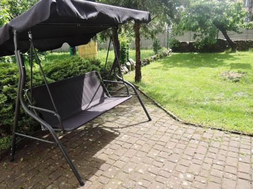 a swing chair with a black canopy in a yard at House in Nowogard by Lake Nowogardzkie in Wyszomierz