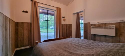 een slaapkamer met een bed en een groot raam bij Gite Haras du Bois de Formerie in Formerie