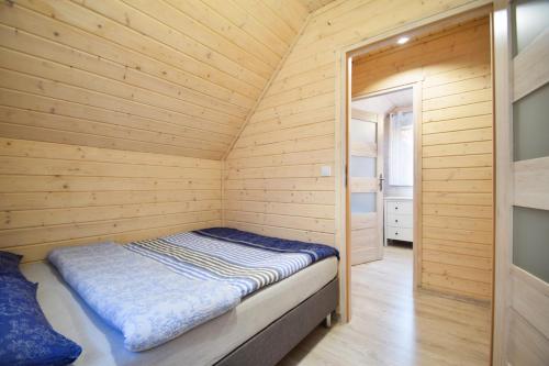 a small bedroom with a bed in a wooden room at Przystanek Pobierowo in Pobierowo