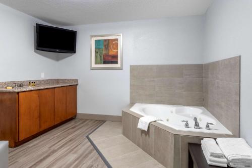 a bathroom with a tub and a tv on the wall at Best Western Plus Orange County in Vidor