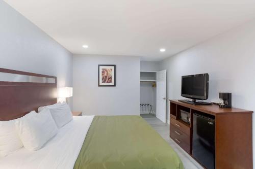 a hotel room with a bed and a flat screen tv at Quality Inn Redding near I-5 in Redding