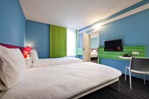 a hotel room with two beds and a television at ibis Styles Duesseldorf-Neuss in Neuss