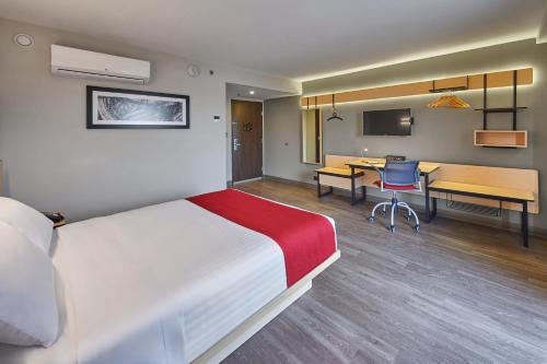 a hotel room with a bed and a desk and a table at City Express by Marriott Guaymas in Guaymas