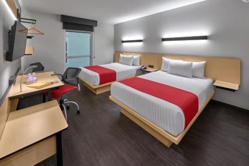a hotel room with two beds and a desk at City Express by Marriott Guaymas in Guaymas