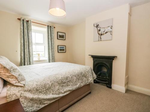 a bedroom with a bed and a fireplace at Mulberry Cottage in Grange Over Sands