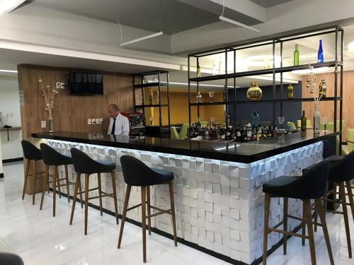 a man standing behind a bar with stools at Hotel Aeropuerto in Mexico City
