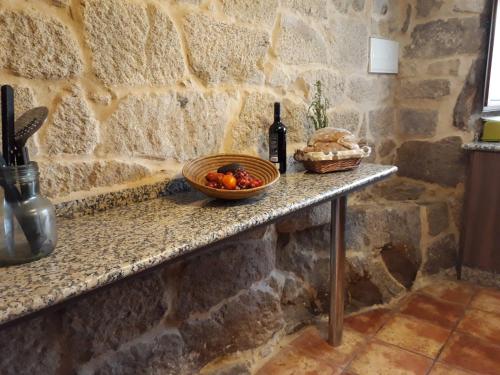 una mesa con un bol de fruta y una botella de vino en Casa de pueblo en San Estevo Ribas de Sil, en Ourense