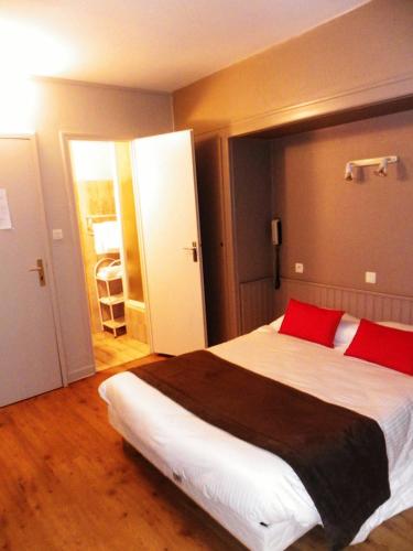 a bedroom with a large bed with red pillows at Hôtel Du Port in Les Sables-dʼOlonne