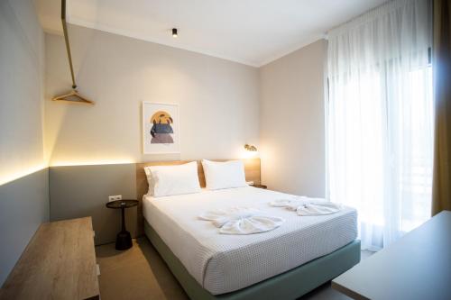a bedroom with a bed with white sheets and a window at Marineiko Luxury Apartments in Ierissos