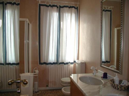 ein Badezimmer mit Waschbecken, Toilette und Spiegel in der Unterkunft At Home a Palazzo in Venedig