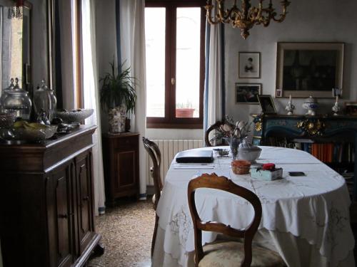 ein Esszimmer mit einem Tisch mit einer weißen Tischdecke in der Unterkunft At Home a Palazzo in Venedig