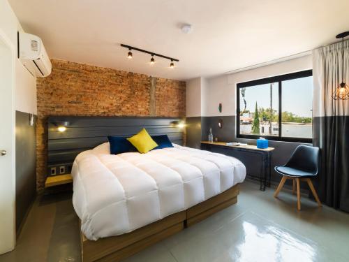 a bedroom with a large bed with a brick wall at Hotel NEXT in Guadalajara