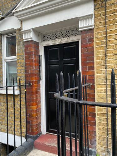 a black door of a brick house with a fence at Flat in Tower Bridge in London