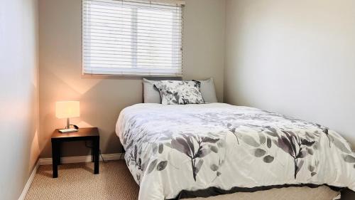 um quarto com uma cama, um candeeiro e uma janela em Lovely 2 Bedroom apartment em Camrose