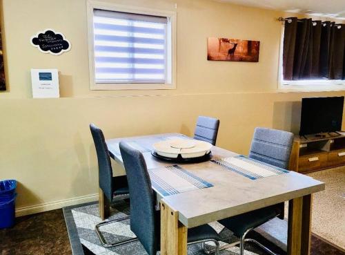 a dining room table with blue chairs and a television at Spacious Basement suite in Camrose