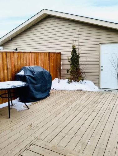 a house with a fence and a wooden deck at Spacious Basement suite in Camrose