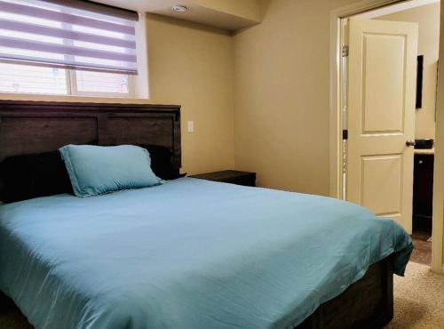 a bedroom with a large bed with a blue pillow at Spacious Basement suite in Camrose