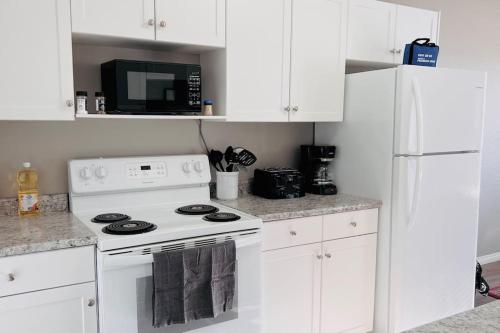 eine weiße Küche mit einem Herd und einer Mikrowelle in der Unterkunft Spacious 2-bedroom apartment in Camrose
