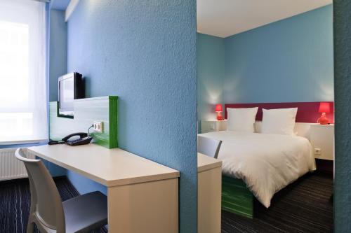 a hotel room with a bed and a desk with a computer at ibis Styles Duesseldorf-Neuss in Neuss