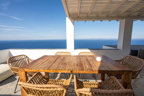 a wooden table and chairs on a balcony with the ocean at Astarte Luxury Apartments in Artemonas