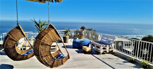 einen Balkon mit 2 Schaukelstühlen und Meerblick in der Unterkunft African Vibes Camps Bay in Kapstadt